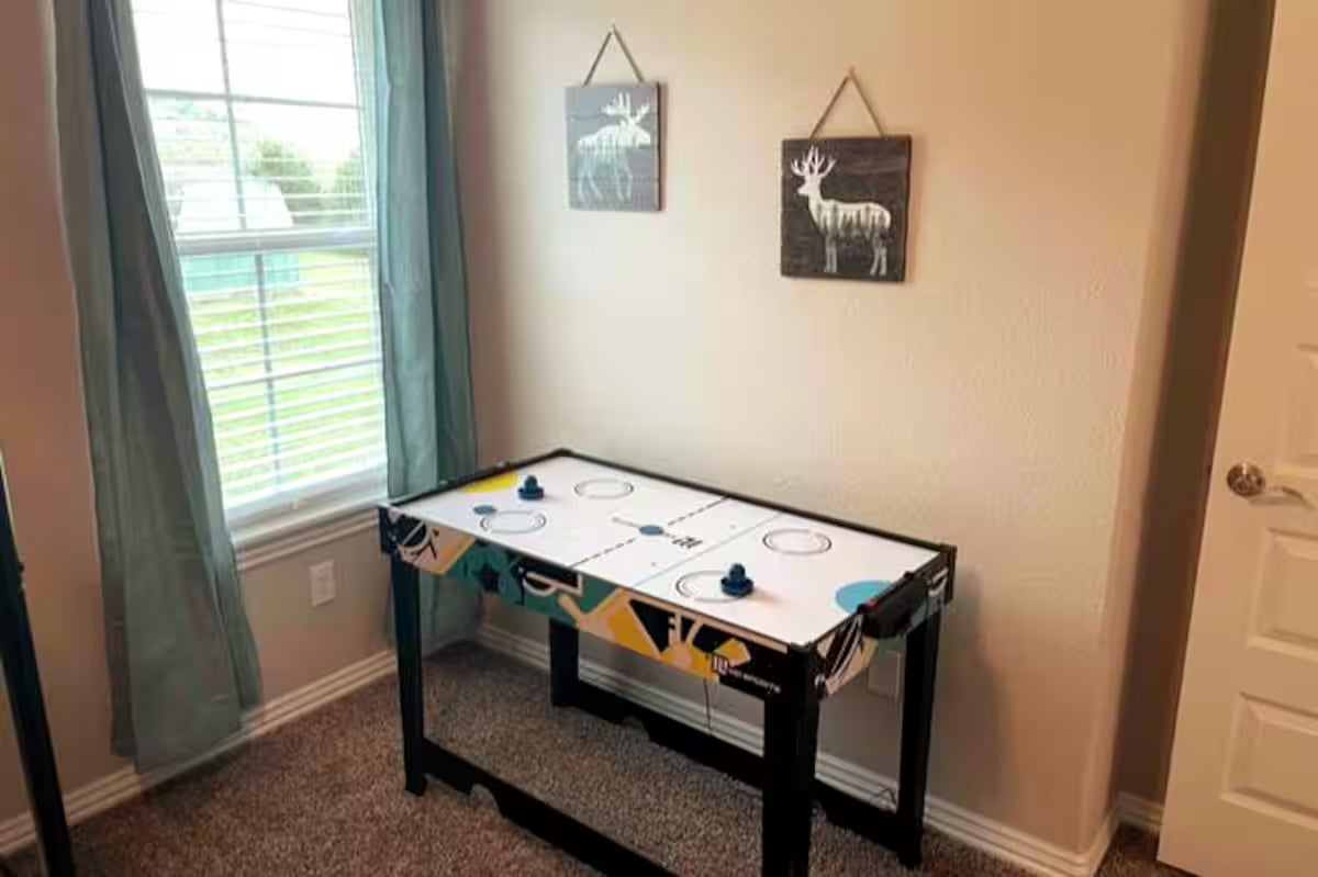 Air hockey table in a room with a window and wall decorations.