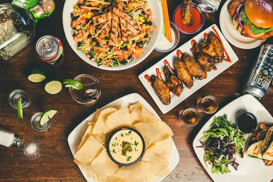 A variety of dishes and drinks on a wooden table, suggesting a meal shared by multiple people
