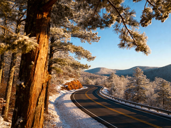 Scenic winter road winding through the Ozark Mountains toward Holiday Island, Arkansas, light dusting of snow on evergreens, clear blue sky, safe driving conditions on a well-maintained highway, professional travel photography style