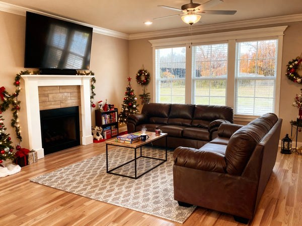 A cozy interior view of a luxury cabin with large windows showing rain falling over Table Rock Lake, featuring a warm fireplace, board games on a coffee table, and hot chocolate mugs, with Ozark fall foliage visible through the raindrops