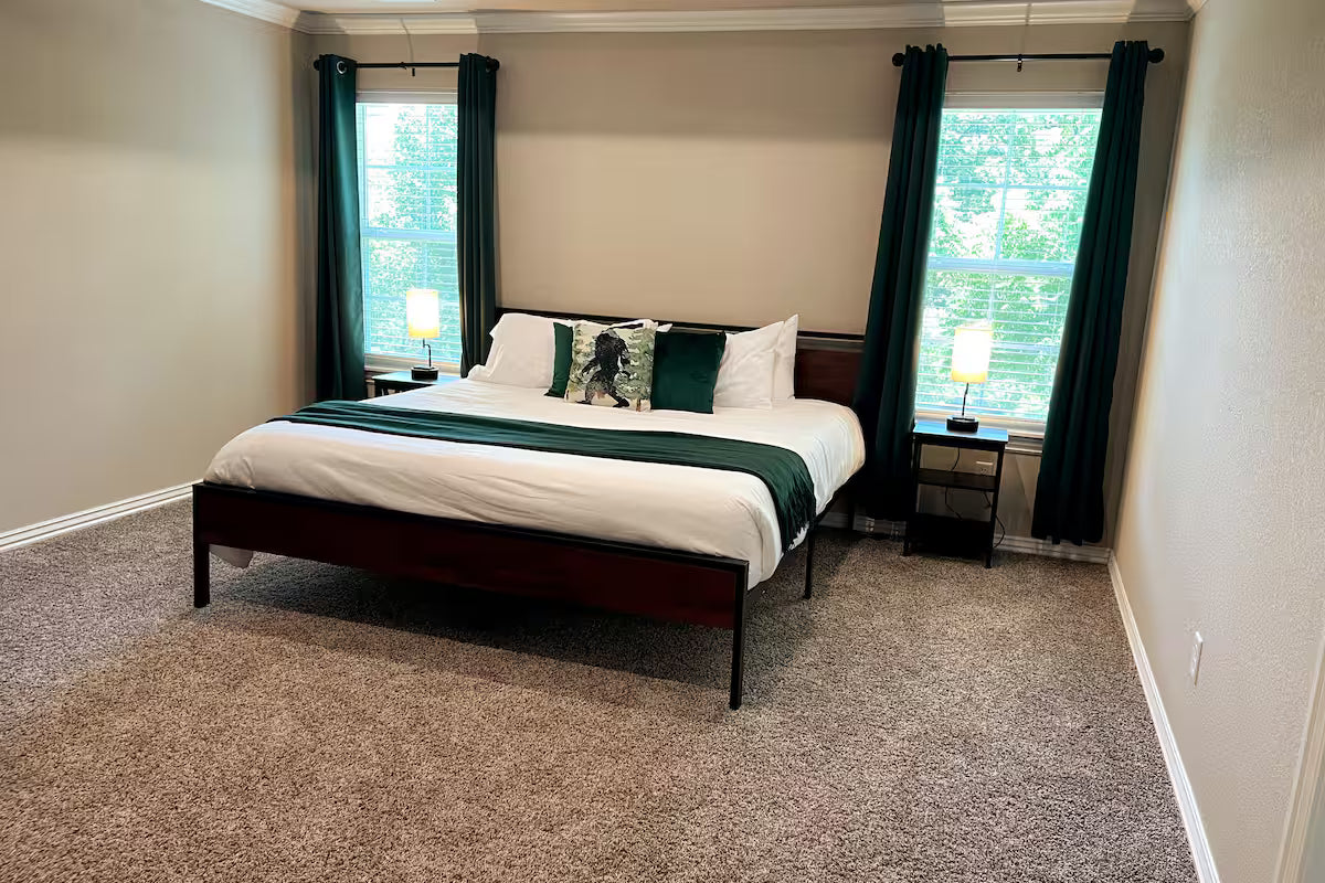 Bedroom with a bed, nightstands, and curtains in a home setting