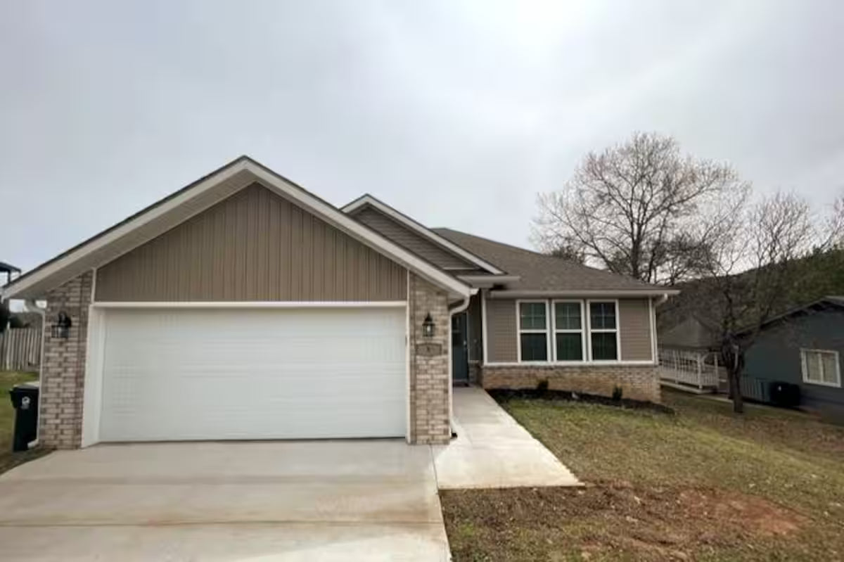 Front view of the house of Woodland Retreat. It has a garage and driveway on a cloudy day