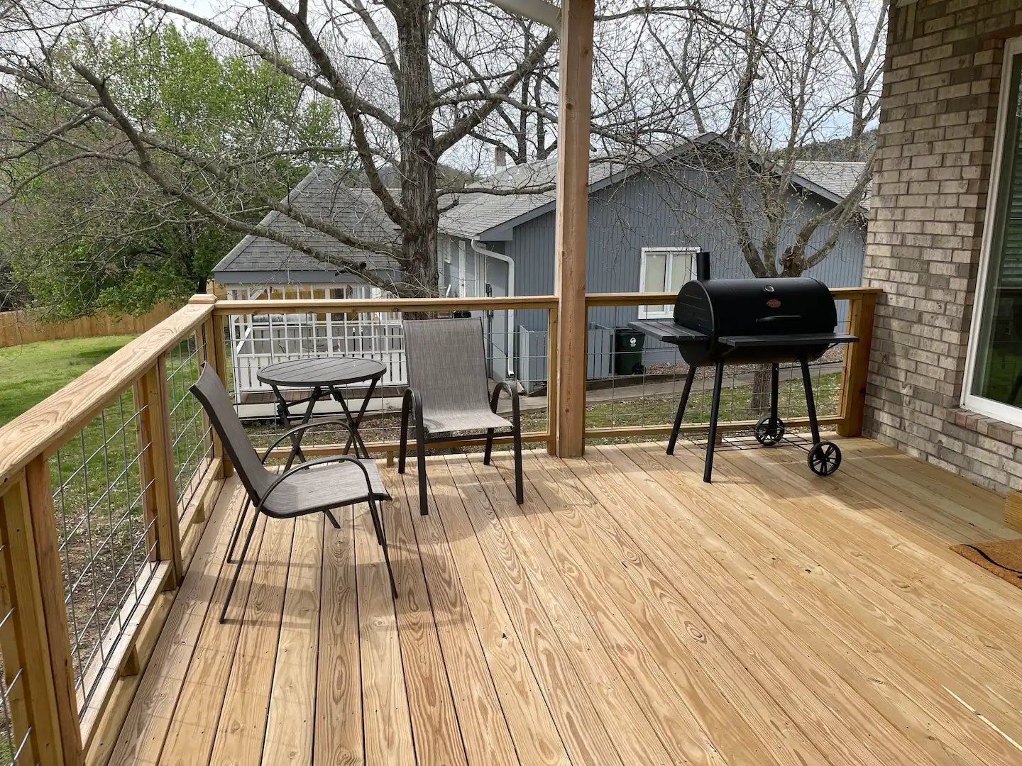 Wooden deck with outdoor furniture and a grill on a residential property.